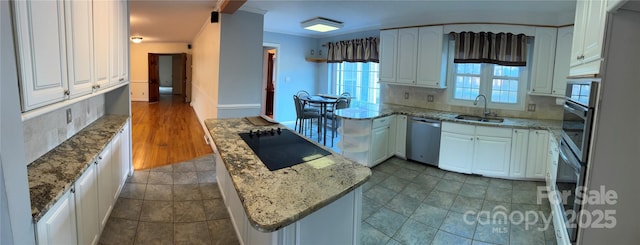 kitchen with light stone counters, a sink, white cabinetry, appliances with stainless steel finishes, and backsplash