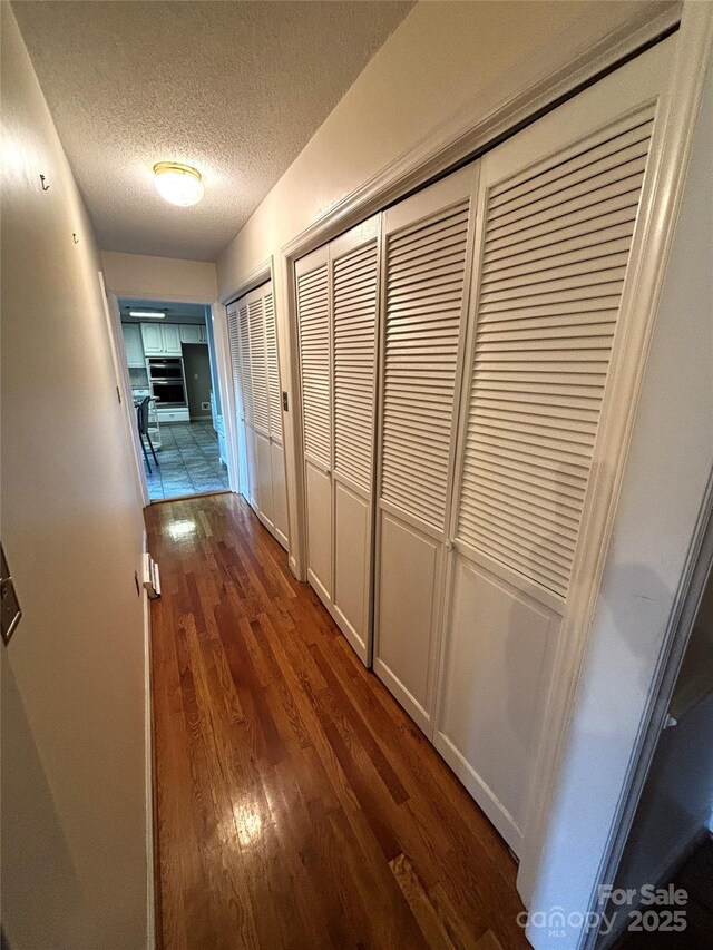 hallway featuring a textured ceiling and dark wood-type flooring