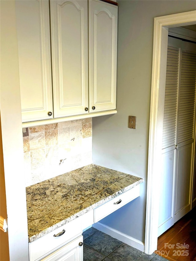 kitchen featuring light stone countertops, tasteful backsplash, and white cabinets