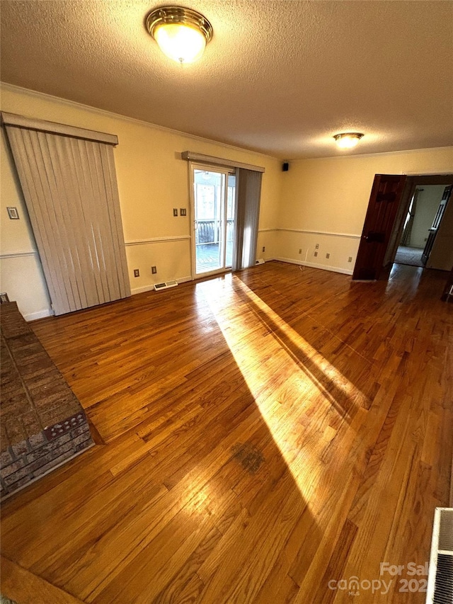 unfurnished living room with visible vents, a textured ceiling, and wood finished floors