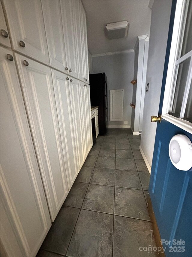 corridor featuring dark tile patterned floors and baseboards