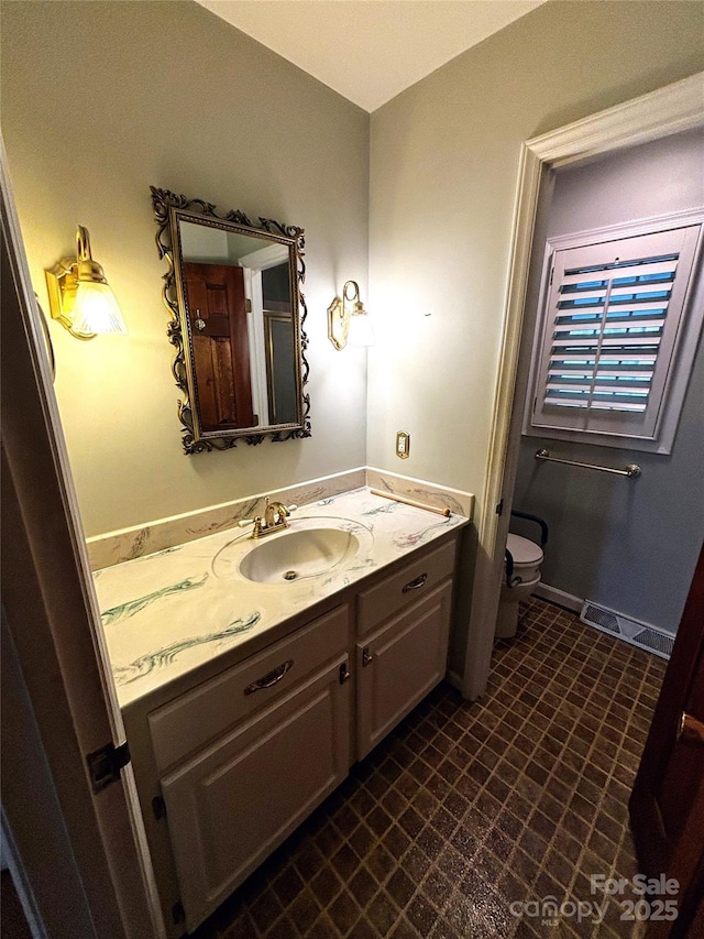 bathroom with vanity, toilet, and baseboards