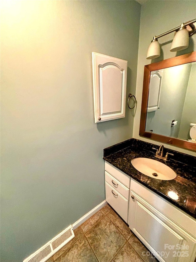 half bath with visible vents, vanity, and baseboards