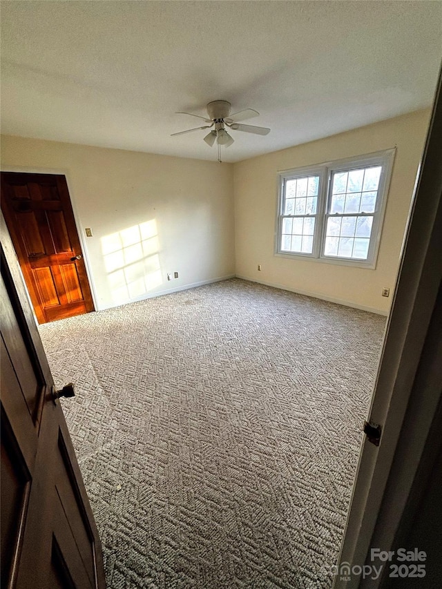 carpeted spare room with a ceiling fan and a textured ceiling