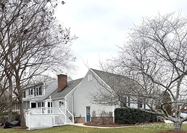 view of property exterior featuring a lawn, a chimney, and a wooden deck