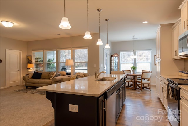 kitchen featuring light stone counters, a breakfast bar, appliances with stainless steel finishes, a kitchen island with sink, and a sink