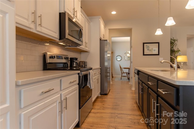 kitchen featuring decorative backsplash, appliances with stainless steel finishes, light countertops, white cabinetry, and a sink