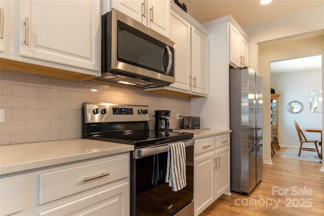 kitchen with white cabinets, tasteful backsplash, stainless steel appliances, and light countertops