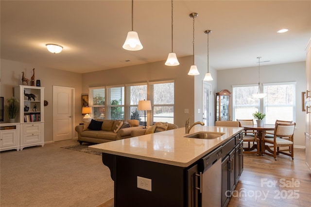 kitchen featuring dishwasher, plenty of natural light, a sink, and decorative light fixtures