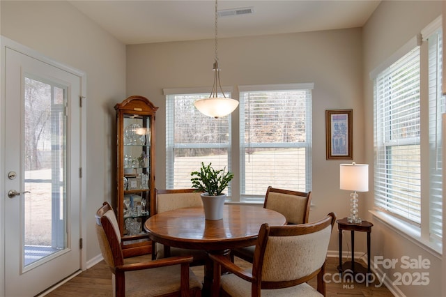 dining space with baseboards, visible vents, and wood finished floors