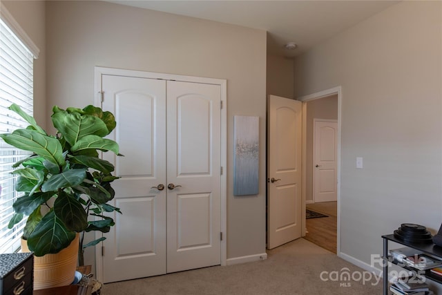 bedroom featuring baseboards, a closet, and light colored carpet