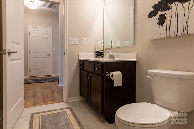 bathroom featuring visible vents, toilet, vanity, tile patterned flooring, and baseboards