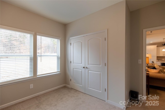 bedroom featuring baseboards, a closet, and light colored carpet