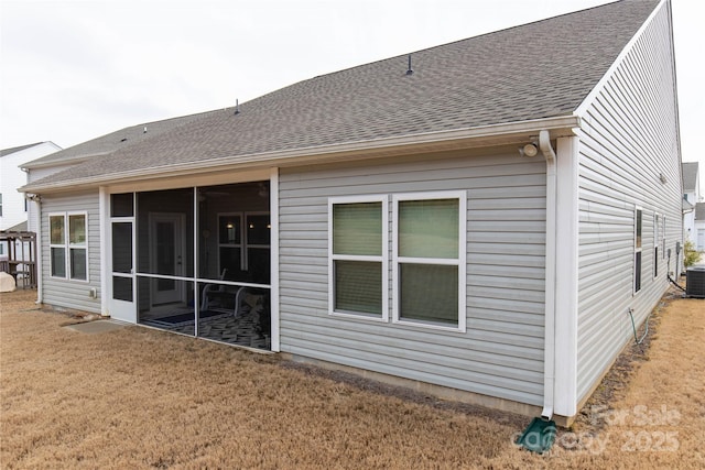 back of property featuring a sunroom, a lawn, and roof with shingles