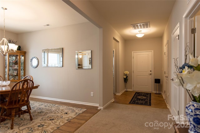 interior space with visible vents, a notable chandelier, baseboards, and wood finished floors