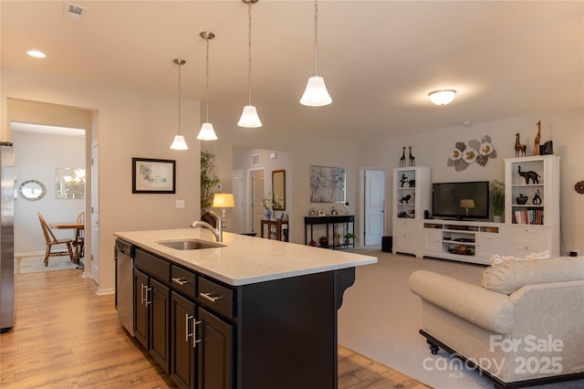 kitchen featuring open floor plan, light countertops, a sink, and light wood-style flooring