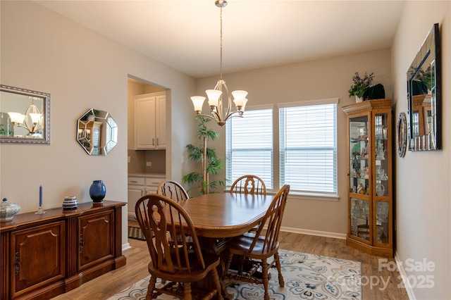 dining area featuring light wood-type flooring, baseboards, and an inviting chandelier