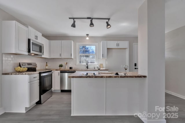 kitchen with stainless steel appliances, light wood-style floors, backsplash, and white cabinets