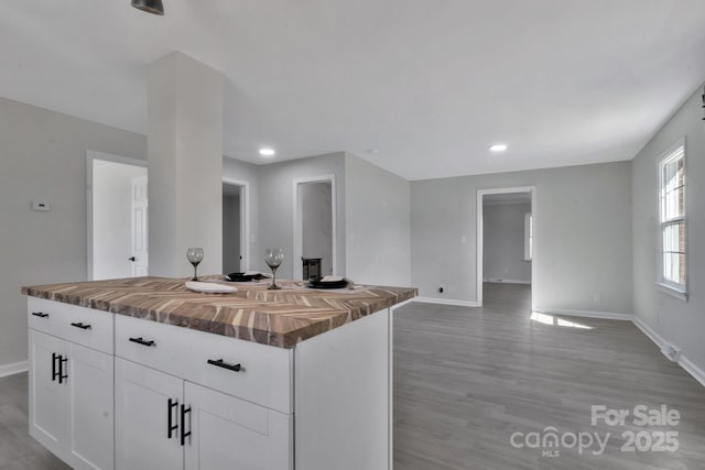 kitchen with butcher block countertops, white cabinetry, open floor plan, a center island, and light wood finished floors