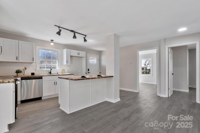 kitchen featuring tasteful backsplash, baseboards, white cabinets, dishwasher, and wood finished floors