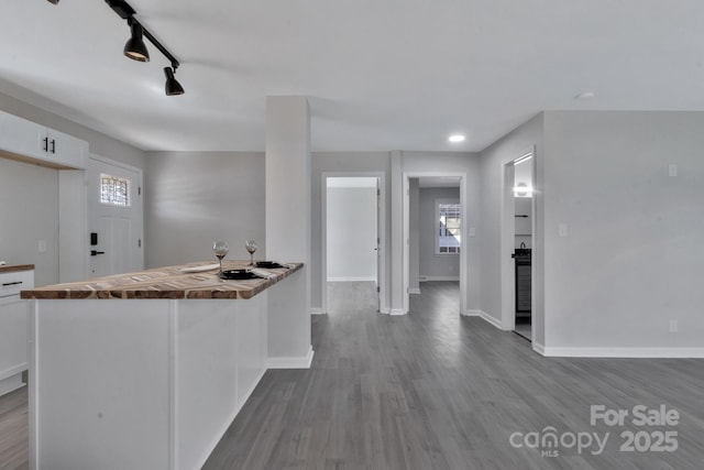 kitchen with light wood-style flooring, rail lighting, white cabinetry, and baseboards