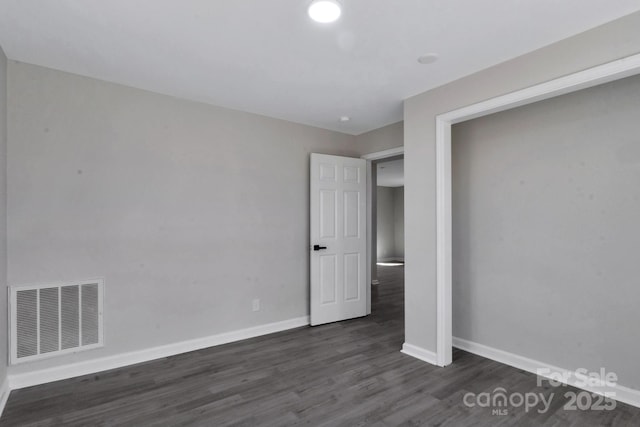 unfurnished bedroom featuring baseboards, visible vents, and dark wood-type flooring