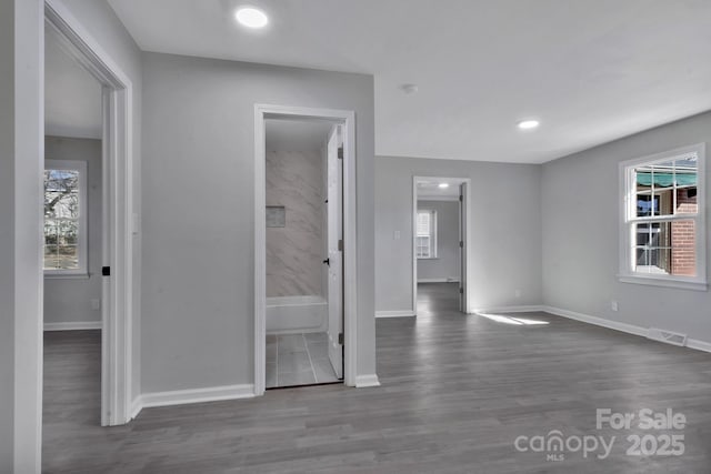 unfurnished room featuring baseboards, visible vents, dark wood-type flooring, and a wealth of natural light