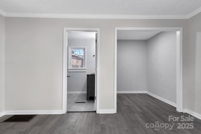 unfurnished bedroom featuring dark wood-style floors, baseboards, visible vents, and crown molding