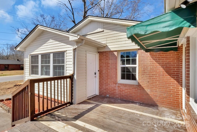 property entrance with a deck and brick siding