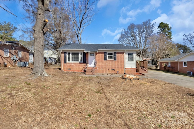 view of front facade with driveway, brick siding, crawl space, and roof with shingles