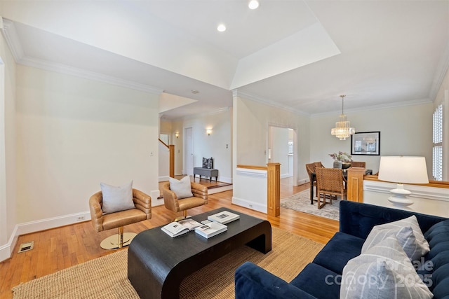 living room with light hardwood / wood-style flooring, ornamental molding, and a chandelier