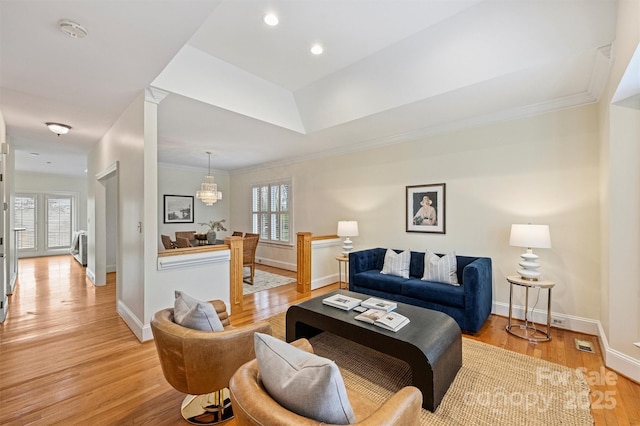 living room with crown molding, a wealth of natural light, and light wood-type flooring