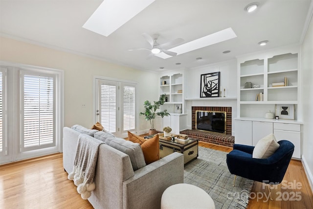 living room featuring a skylight, a brick fireplace, and light wood-type flooring