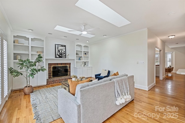 living room with light hardwood / wood-style flooring, a fireplace, a skylight, and plenty of natural light