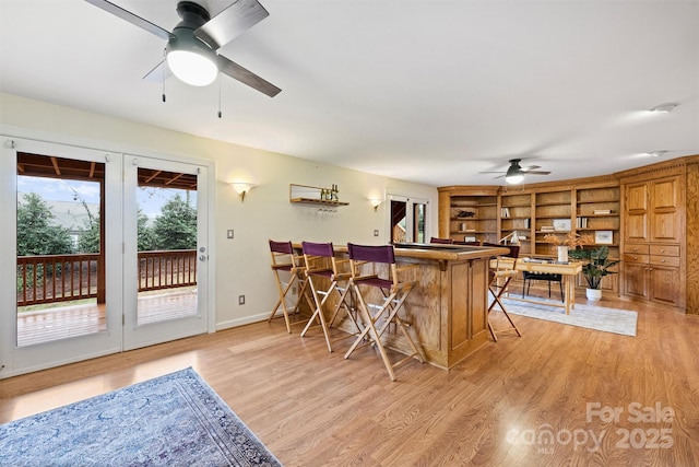 interior space with ceiling fan, indoor bar, and light wood-type flooring