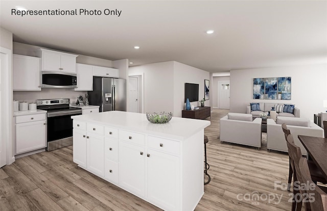 kitchen featuring a breakfast bar area, appliances with stainless steel finishes, white cabinetry, a kitchen island, and light wood-type flooring