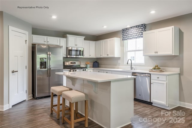 kitchen with a sink, white cabinetry, light countertops, appliances with stainless steel finishes, and a center island