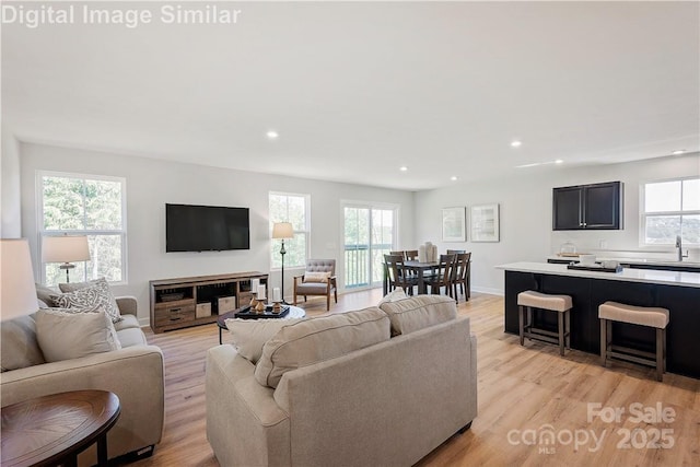 living area featuring a healthy amount of sunlight, light wood-style floors, baseboards, and recessed lighting