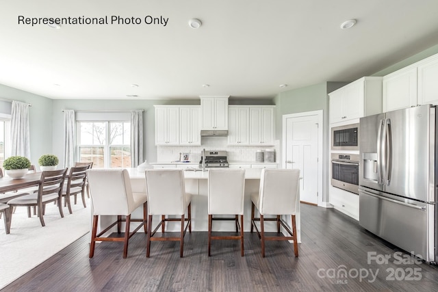 kitchen with white cabinetry, a breakfast bar area, stainless steel appliances, and an island with sink