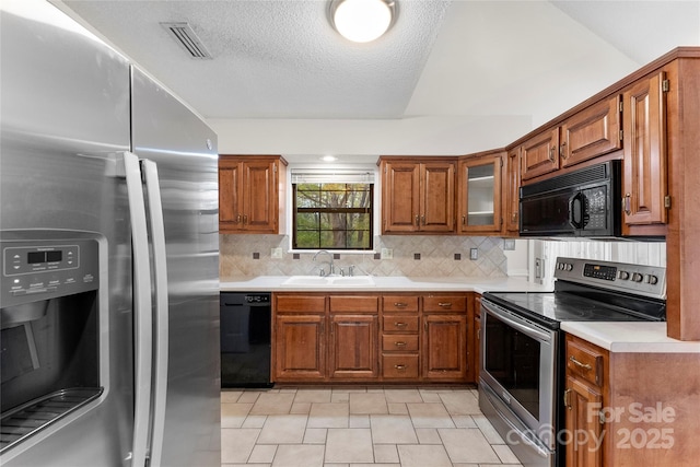 kitchen featuring sink, backsplash, a textured ceiling, and black appliances