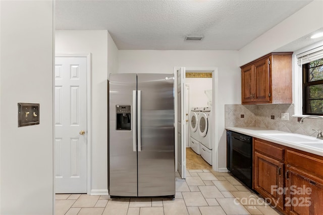 kitchen with sink, tasteful backsplash, stainless steel fridge with ice dispenser, dishwasher, and washing machine and dryer