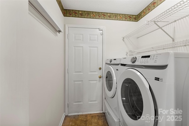 clothes washing area with washing machine and clothes dryer and a textured ceiling