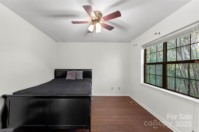 unfurnished bedroom featuring ceiling fan, a textured ceiling, and dark hardwood / wood-style flooring