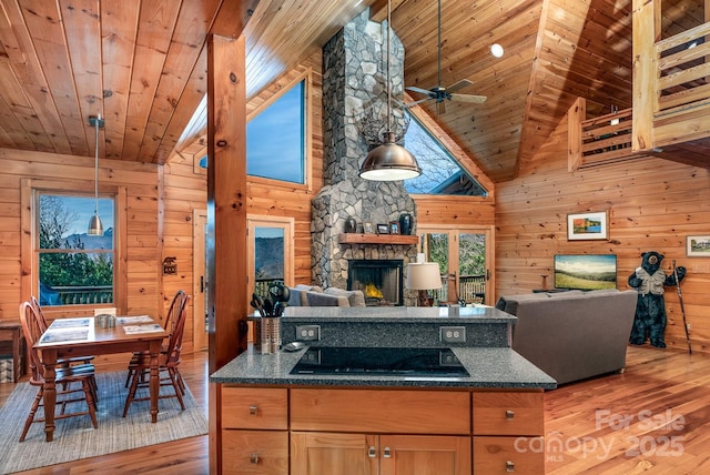 kitchen with wood walls, decorative light fixtures, black electric stovetop, wooden ceiling, and light wood-type flooring