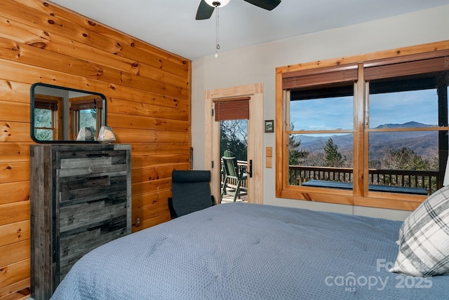 bedroom with ceiling fan, access to exterior, and a mountain view