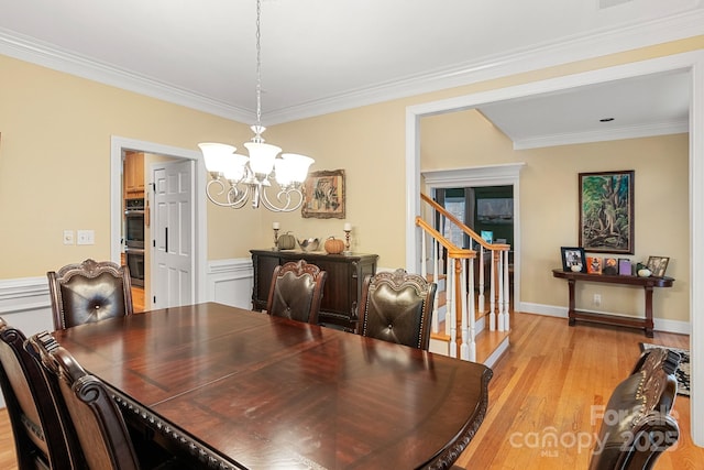 dining space with ornamental molding, a chandelier, and light hardwood / wood-style floors