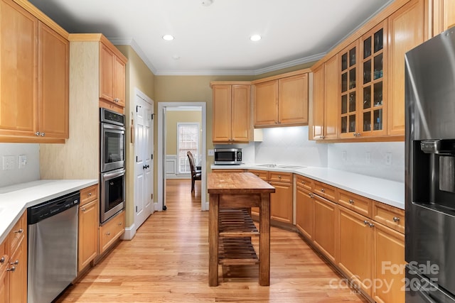 kitchen with tasteful backsplash, ornamental molding, appliances with stainless steel finishes, and light wood-type flooring