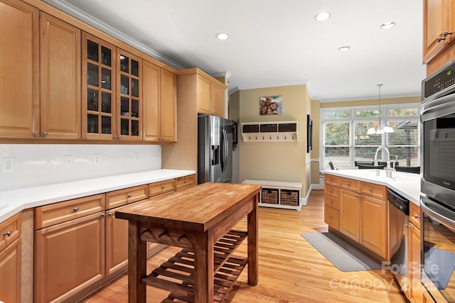 kitchen with sink, light wood-type flooring, hanging light fixtures, stainless steel appliances, and an inviting chandelier