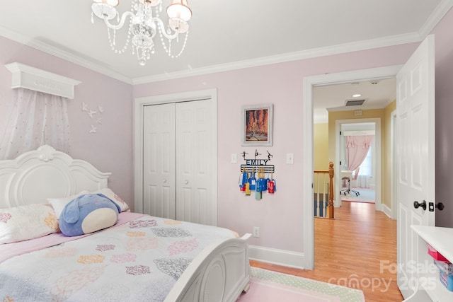 bedroom with crown molding, an inviting chandelier, a closet, and light wood-type flooring