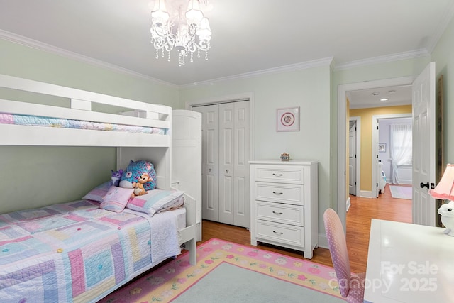 bedroom featuring crown molding, a closet, light hardwood / wood-style flooring, and a notable chandelier